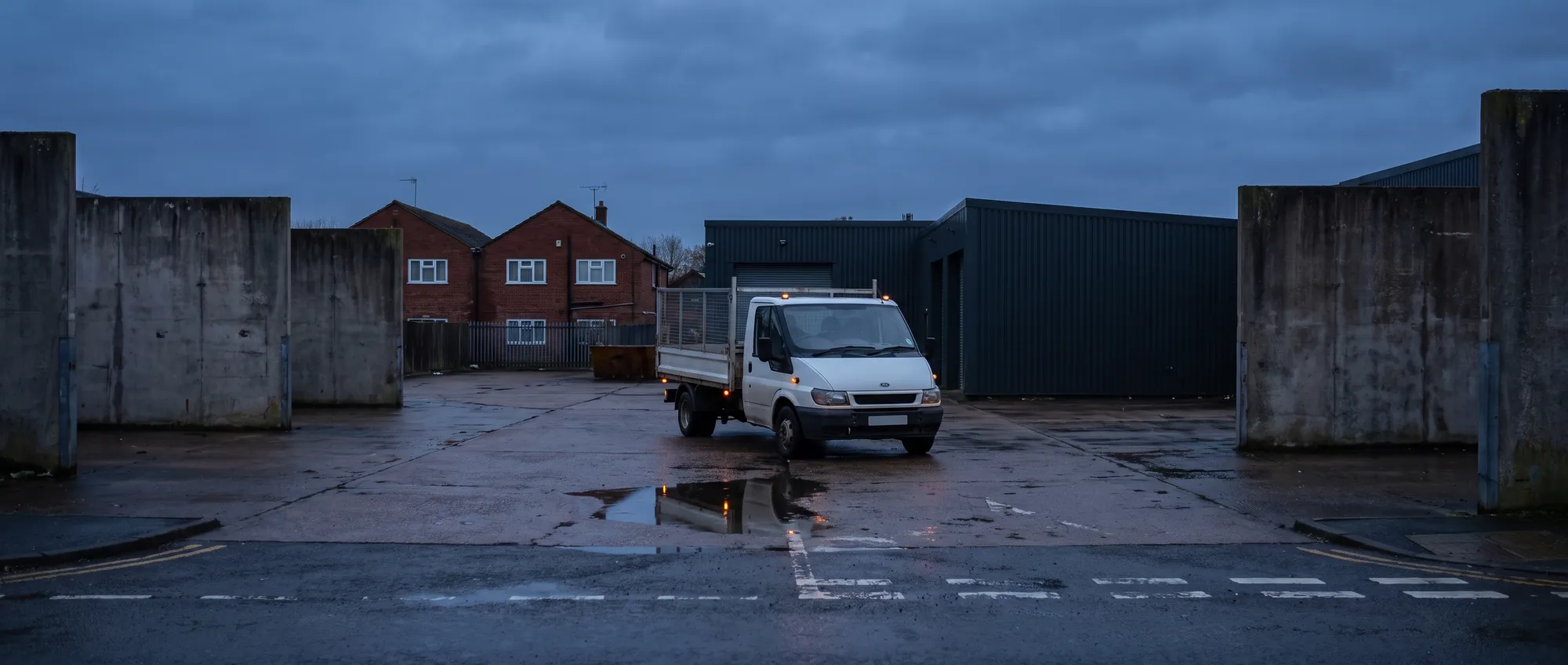 A cage tipper parked at the yard at dusk with its sidelights on